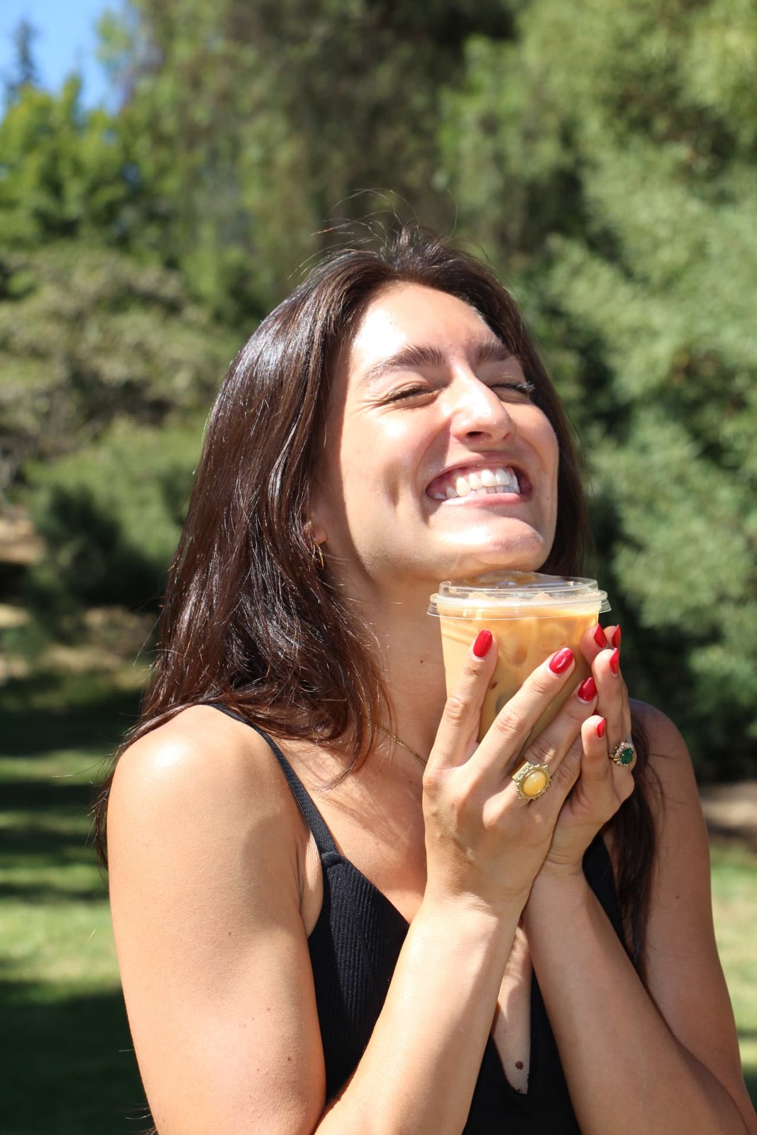 A guest laughing while holding an iced latte from Ayni Café